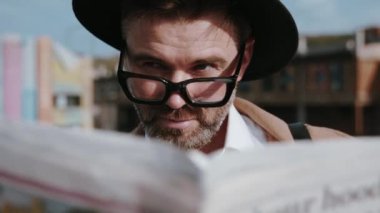 Suçluların şehrinin çatısında dikilen gazeteyle gözlerini kapatan zeki dedektifin başkalarını izlediği yakın plan görüntüsü. Retro tarzı erkek portresi.