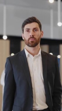Resmi takım elbiseli yakışıklı beyaz iş adamı kalabalık bir iş merkezi salonundan geçiyor. Çekici girişimci.