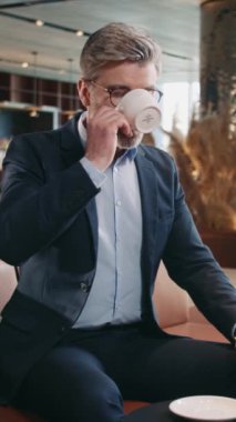 Kafedeki masada oturan, kahve içen, saatine bakan iyi giyimli bir iş adamı. Gri saçlı, takım elbiseli, gözlük takan güzel sakallı bir adam. Zaman kavramı. Toplantı