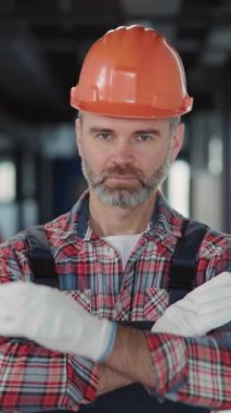 Kendini işine adamış bir inşaat işçisi, işine odaklanırken turuncu bir şapka ve ekose gömlek giyiyor.