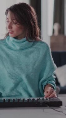 Mavi kazaklı bir kadın masasında müzik besteler, klavyesine yazar. Sonra kulaklıkla klavye çalıyor, yeteneğini gösteriyor.