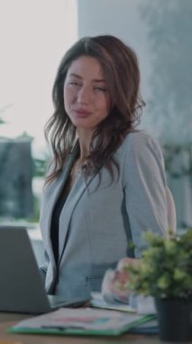 Profesyonel giyinmiş kararlı bir kadın bilgisayarını sofistike bir ofis ortamında ustalıkla kullanıyor.