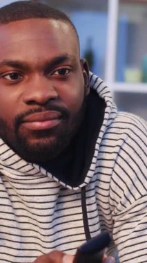 Evde televizyon izleyen, sıradan giysili Afrikalı genç bir adam. Huysuz adam TV kanallarını değiştiriyor. İçeride. Yakın plan.