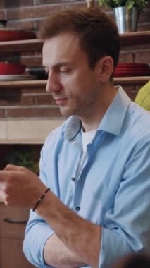 Mutfak masasına dayanan bir akıllı telefondan ciddi şekilde konsantre olmuş bir adam haberlere göz atıyor. Başarılı iş adamlarının profili cep telefonundan haberleri okuyor ve evde dinleniyor.