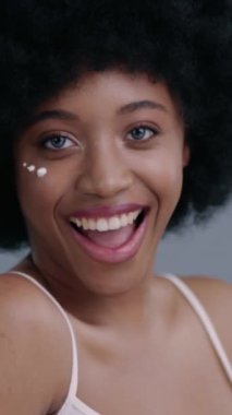 Güzel afro saç stili olan neşeli genç bir kadın yenilikçi ve göz alıcı makyajını gururla sergiliyor.