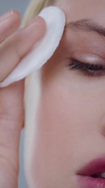 Cilt bakımı için pamuk pedi kullanan birinin yakın plan fotoğrafı, özellikle makyaj temizliği için.