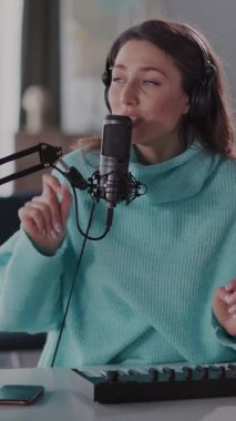 Bu videoda bir kadın, mikrofona tutkulu bir şekilde şarkı söylüyor, rahat kıyafetler içinde, müziğe dalmış, duygularını ve yaratıcılığını aktarıyor.