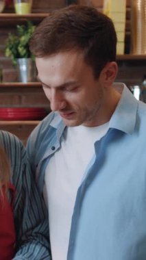 Mutlu, sevecen romantik çiftin portresi, kameraya gülümseyen, işten sonra birlikte yemek pişiren, modern mutfakta..