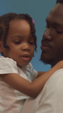 Bir adam küçük bir kızı kucağına alıp, hassas bağlarını sergiliyor. Video, aile bağlarının neşe, sevgi ve güzelliğini vurguluyor.