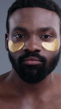 Huzurlu, sakin bir adam lüks altın göz bantlarıyla süslenmiş, cildini ve kişisel bakım rutinlerini ön plana çıkaran