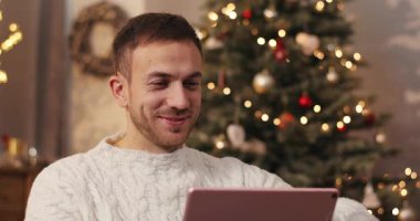 Elinde dijital tablet sakallı çekici bir genç. Eleman ekrandaki elektronik aletlere dikkatle bakıyor ve gülümsüyor. Kutlama atmosferi. Kapalı