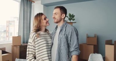 Neşeli bir çift yeni evlerinde sevgi ve yeni başlangıçları sembolize eden taşınan kutularla kucaklaşır..