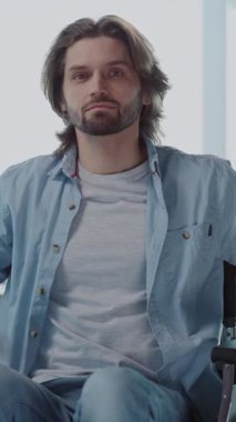 Engelli, genç, yakışıklı, ofis müdürü iş adamı patron tekerlekli sandalyede oturmuş kameraya gülümsüyor..