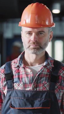 Kendini işine adamış ve işine odaklanmış bir inşaat işçisi olay yerinde ekose gömlekle birlikte turuncu bir şapka takıyor.