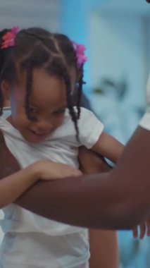 Yürek ısıtan bir sahne ortaya çıkıyor. Bir baba kızını kucaklıyor ve bağlarını vurguluyor. Bir kadın saçlarını örüyor, aile sevgisini ve neşesini gösteriyor.