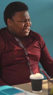 Kestane rengi gömlekli bir adam masasında derin düşüncelere dalarken, kırmızı gömlekli bir adam da kahveyi, rahatlamayı ve üretkenliği dengelemeyi seviyor.