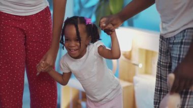 Gülümseyen Afro-Amerikan ebeveynler küçük kızlarını odada büyütüyorlar. Mutlu çocukluk, çocuklar ve insanlar konsepti.