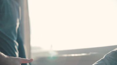 Oturma odasında kavga üstüne kavga için el ele tutuşan genç adam. Birbirini seven bir çift pencerenin yanında el sıkışıyor. Günaydın..