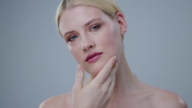 Güzel moda kızı yumuşak hareketlerle berrak, taze yüzüne dokunuyor. Yarı çıplak, şehvetli genç bir kadının güzellik salonunda spa tedavisi görmesi portresi..