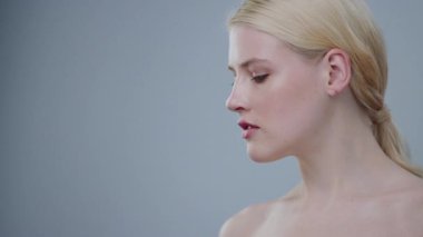 Çıplak omuzlarıyla aşağıya bakan sarışın bir modelin muhteşem profili. Makyajsız çıplak bir kızı cezbetmek güzel çenesini eliyle vurguluyor..