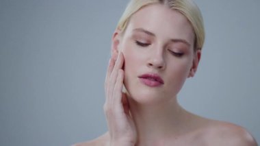 Mükemmel çıplak, şehvetli sarışın kızın portresi. Kusursuz parlak tenine hafifçe dokunuyor. Arka planda tek başına duruyor..