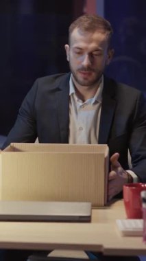 İşten kovulan kendine güvenen genç bir adam çalışma alanını terk ediyor ve kişisel eşyalarını karton kutuya koyuyor. İşsizlik. İş krizi konsepti.