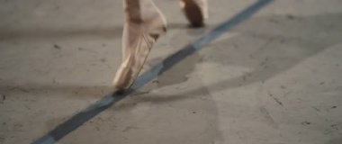Sahne ışıkları bir dansçının ayağında parlıyor, bale ayakkabıları giymiş, gösterinin zarafetini ve sanatını sergiliyor.