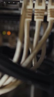 Bu video, dijital iletişimi sembolize eden birbirine bağlı kablolar ve bir bilgisayarın yakın çekimlerini içeren karanlık bir ortamda teknolojinin karmaşıklığını araştırıyor.
