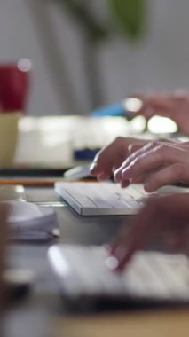 Dinamik ve işbirlikçi bir çalışma ortamı içinde aktif olarak klavyelere yazı yazan ellerin yakın görüntüsü