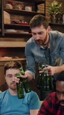 Kotlu bir adam yeşil şişeleri tutarken rahat ve kırsal bir mutfak ortamında duruyor ve sıcak bir hava yaratıyor.