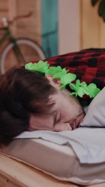 Genç bir adam rahat bir kanepede huzurlu bir şekilde uyuyor, rahat bir ortamda güzel bir çiçek kolyesiyle süslenmiş.