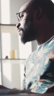 Düşünceli bir adam uzaklara bakar, çiçekli bir gömlek ve gözlük giyerek görünüşünü güçlendirir.