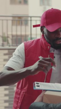 Kapalı yüz kuryesi Afro-Amerikan, teslimat cihazı, karton teknoloji kutusu siparişi, posta kutusu postası, sakallı, lojistik postacı...