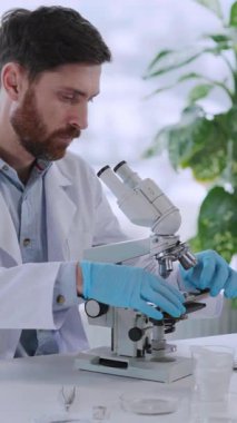 Beyaz üniformalı Beyaz Sakallı Genç Mikrobiyoloji Doktoru Mikroskop Laboratuvarı Aşı Geliştirme Ekipmanı.