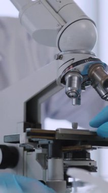 Mikroskop altında genç bir tıp çalışanı laboratuvarda profesyonel araştırma yapan bakteri aşısı geliştiriyor..