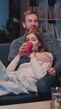 Çekici, genç, beyaz, evli, çekici erkek ve kadın bir çift kanepede uzanıp TV 'de favori komedi filmini izliyorlar..