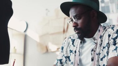 Meşgul Afro-Amerikalı tasarımcının yeni moda koleksiyonu oluşturma sürecine yakından bakınca renkli kumaş örnekleri arasından seçim yapıyor. Terzilik işi, en sevdiğim iş. Rahat bir ofis. Erkek.