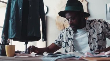 Yorgun genç tasarımcı dinlenmeye karar verir, şapkasını çıkarır, tableti kullanmaya başlar. Sosyal ağlar, rahatlama, mola. Moda blogcusu, güncel kültür. Ağır çekim, erkek portresi.