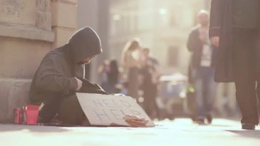 Kalabalık bir caddenin ortasında, şefkatin ve sosyal farkındalığın temalarını vurgulayan yalnız bir figür..