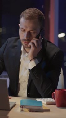 Resmi kıyafetli genç adam ofis eşyalarını karton kutulara doldurup işvereni cep telefonundan aramaya karar verdi..