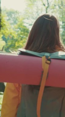 Sırt çantasında yürüyüş ekipmanıyla gezen güzel bir kadının dönüşümlü görüntüsü ormanda yürüyor, etrafına bakıyor, doğanın güzelliğinden hoşlanıyor, saçlarını okşuyor. Hobi, aktif yaşam tarzı.