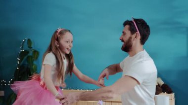 Yakışıklı baba ve kızı yatakta birlikte dans eden periler oynuyorlar. Sevimli küçük prenses neşeleniyor ve babasıyla stüdyoda poz verirken gülümsüyor. Aile