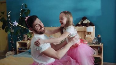 Güzel genç bir aile portresi. Yandan bakan mutlu gülen kız ve babası birlikte sarılıyor ve ev partisi kutlamalarında eğleniyorlar. Aile tatili, sarılmalar ve öpücükler.