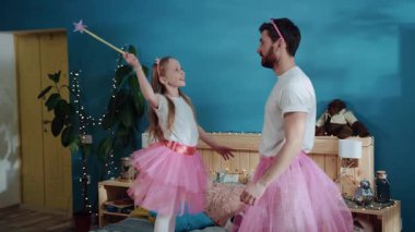Sevgi dolu bir aile partisi. Neşeli baba ve kızı evde büyü yaparak büyü yapıyorlar. Baba ve oğlu peri gibi giyinmiş odada kucaklaşıp gülümsüyorlar..