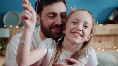 Mutlu baba ve kızının birlikte oynadığı mutlu bir portre. Yakın plan, heyecanlı küçük kızın sihirli değnekle el sallayıp ev partisinde numaralar yaptığı görüntüler..
