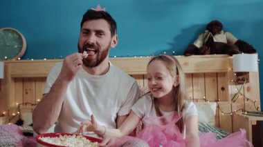 Tatlı sihirli periler baba ve küçük kız stüdyoda poz vererek lezzetli patlamış mısırları yerken ve atarken eğleniyorlar. Aile eğlencesi, doğum günü kutlaması.