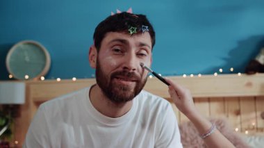 Evde kızıyla oynayan zavallı bir babanın portresi. Küçük kızının makyaj malzemelerini babasının yüzüne sürmesi yatak odasında eğlenmesi..