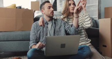 Huzurlu bir ofis ortamında, rahat bir köpek bir dizüstü bilgisayarın yanında taşınan kutuların yanında uzanıyor.