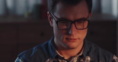 Şık gözlükler tutan ellerin detaylı bir yakın çekimi, rahat ve davetkar bir ortam içinde kareli bir gömlek.