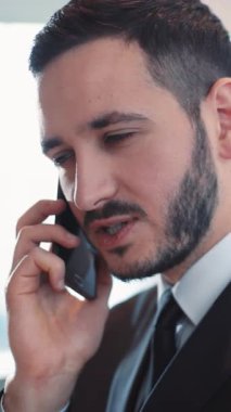 Takım elbiseli bir profesyonel telefonda konuşuyor, kurumsal bir ortamda iletişimi temsil ediyor..